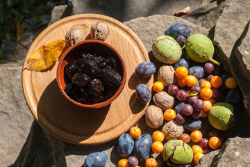 Fresh and dried prunes on plate.