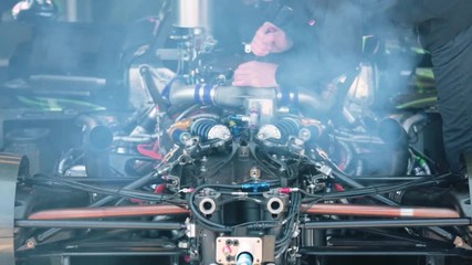 Mechanic testing engine in workshop, tightening some nuts as a final touch.