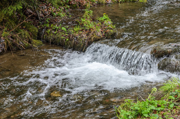 Fototapeta premium Cascades of pure mountain river among the stones