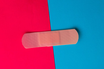 Adhesive bandage or Sticking plaster on a two colored paper background.
