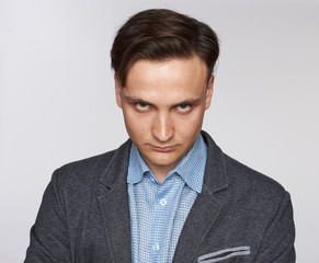 Face of an angry male isolated on a grey background.