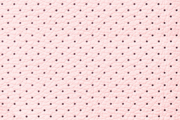 Perforated pink leather texture background, closeup. Light backdrop from wrinkle skin.