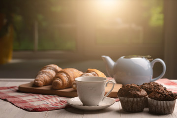 Muffin and croissant on kitchen. Breakfast. Window. Sweet delicious dessert. Food. Wooden table.