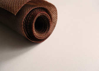  Fabric upholstery brown in a roll at the top left on a white background        