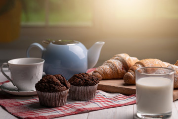 Delicious food. Kitchen. Breakfast. Fresh muffin and croissant. Window. Wooden table. Homemade dessert