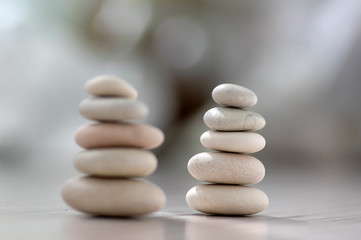 Fototapeta na wymiar Harmony and balance, two cairns, simple poise pebbles on wooden light white gray background, simplicity rock zen sculpture