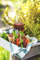 jamon and vegetable sandwiches in a basket, grapes and berry juice, outdoor picnic, close-up