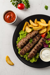 Traditional cevapcici served with baked potatoes. Flat lay. Stone background.