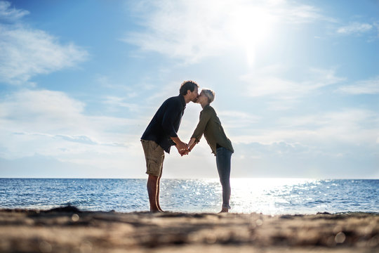 Young couple standing outdoors on beach, kissing. Copy space.