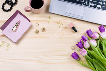 Feminine office desk with stationery, laptop, fashion accessories, flowers and make up products. Woman work desk lay out