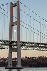 moon framed in by a suspension bridge at sunset
