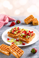 Belgian waffles with fruits strawberries and kiwi on white plate closeup. Tasty healthy breakfast
