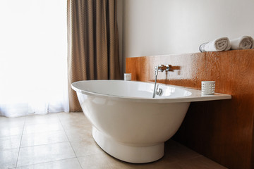 Fototapeta na wymiar Stylish snow-white bathtab in a modern bathroom. Contemporary bathroom interior. Luxury lifestyle