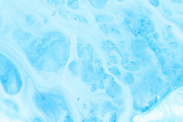 Abstract art texture background. White emulsion flowing over sky blue shimmering surface. Beautiful paint with bubbles.