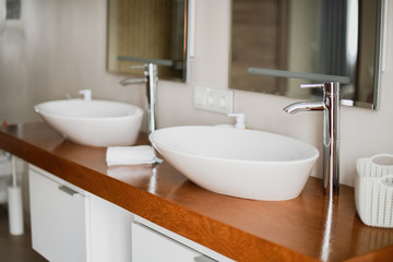 Fototapeta na wymiar Modern stylish washbasins with chrome taps. Luxury lifestyle. Close-up, selective focus Wood texture