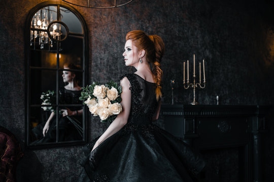 Attractive woman in black dress in medieval interior