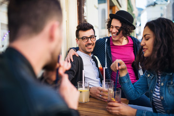 A group of young friends sitting in an outdoor cafe, talking.
