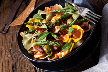 Pasta salad with green asparagus, olives and parma ham