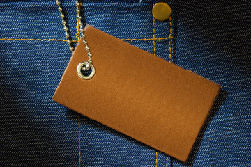 Leather label of product price and stainless steel ball chain on denim clothing. The concept of...
