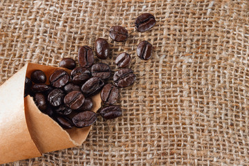 The coffee grains scattered on a table near a cup with coffee