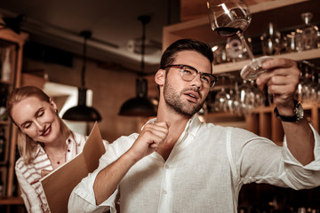 Attentive bearded male person looking at glass