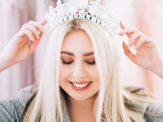 Fashion accessories. Closeup portrait of smiling lady wearing tiara, creating look for special occasion.