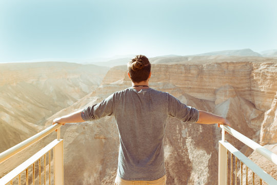Yong free man looking across the desert standing on a cliff