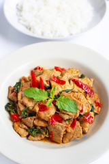 Stir-fried hot and spicy pork with holy basil on white.