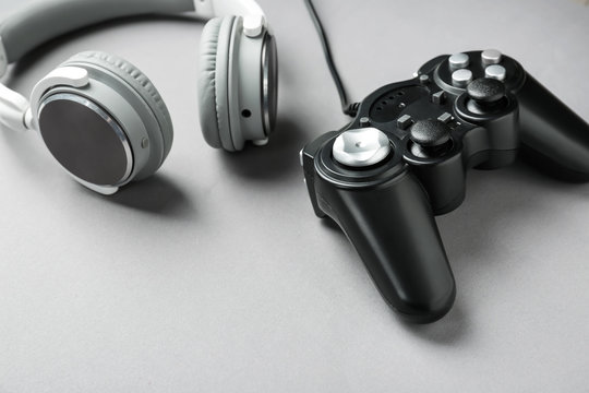 Modern game pad and headphones on grey background