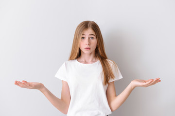 Confused teenage girl on light background