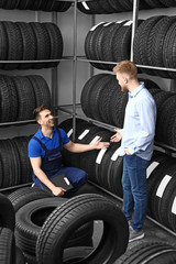 Obraz na płótnie Canvas Seller helping man to choose tires in car store