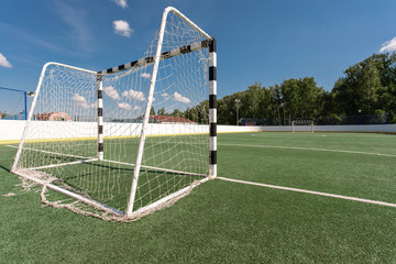 Football field. Artificial surface, green grass. Sport outdoors. Goal nets, white lines, circle center.