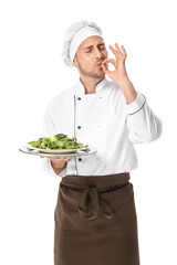 Handsome male chef with salad on white background