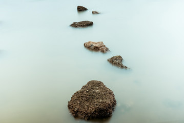 Long Exposure Photography of Waves on stone beach waters edge abstract sea background.Thailand.