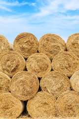 Straw bales on farmland with blue cloudy sky