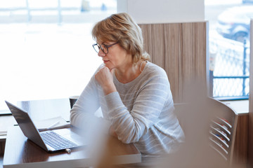 middle-aged woman business in workplace in cafe, office, she's working on her laptop.