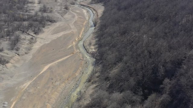 Mining drainage waste on polluted river coast 4K aerial video
