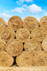 Straw bales on farmland with blue cloudy sky