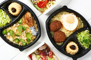 Containers with delicious food on white wooden background