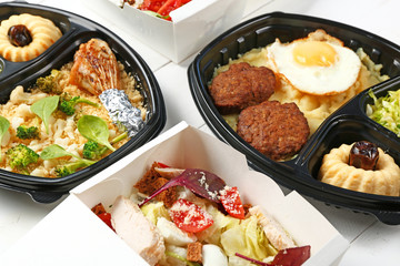 Containers with delicious food on white wooden background