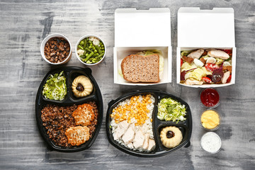 Containers with delicious food on grey background