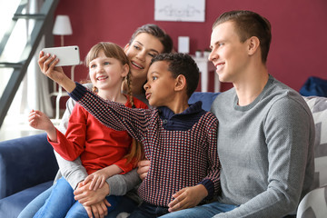 Happy couple with adopted children taking selfie at home