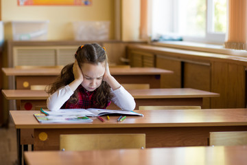 Smiling caucasian girl sitting at desk in class room and hard to learn lessons. Preparation for exams, tests