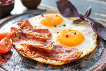 Plate with tasty eggs, bacon and tomato on table, closeup