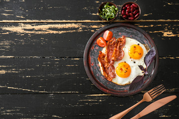 Plate with tasty fried eggs, bacon and tomato on table