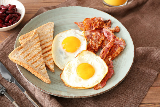 Tasty English breakfast  with fried eggs, bacon, beans and toasts on table