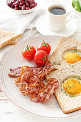 Plate with tasty fried eggs, bacon, toasts and tomato on wooden background