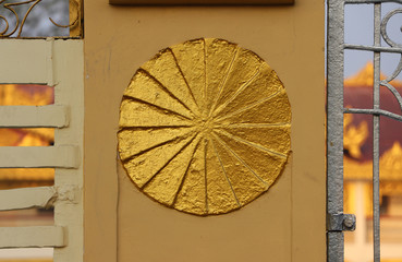 Gold stucco circle on the fence, symbolic of Dharma wheel.