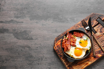 Frying pan with tasty eggs and bacon on grey background - Powered by Adobe