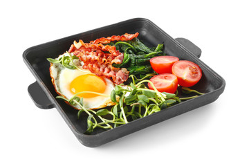 Frying pan with tasty egg, bacon and tomato on white background